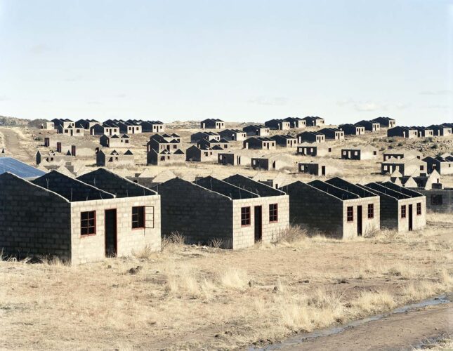 David Goldblatt, Incomplete houses, part of a stalled municipal development of 1,000 houses. The funding allocation was made in 1998, building started in 2003. Officials and a politician gave various reasons for the stalling of the scheme: Shortage of water, theft of materials, problems with sewage disposal, problems caused by the high clay content of the soil, and shortage of funds. By August 2006, 420 houses had been completed, Lady Grey, Eastern Cape, 5 August 2006, 2006 © The David Goldblatt Legacy Trust